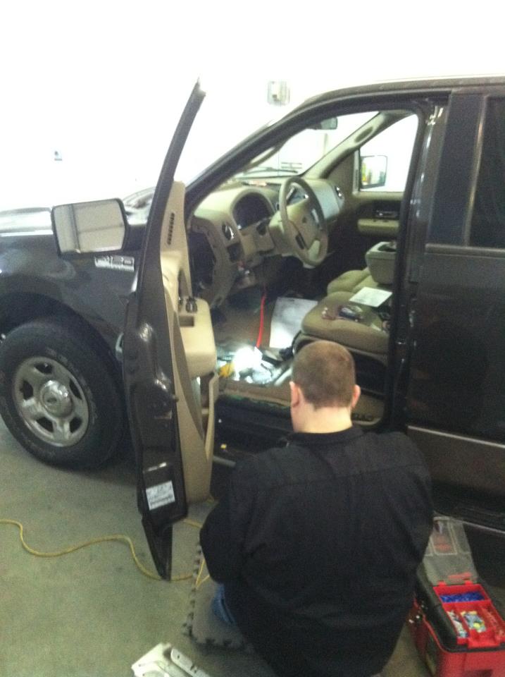 A technician installing a new stereo system in a black truck