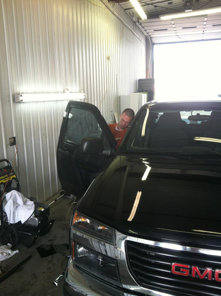 A man inspecting the door of a black truck in the Omaha Stereo Pro shop