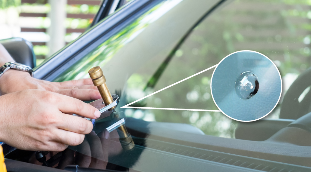 A man holding a tool up to a car windshield to repair a chip