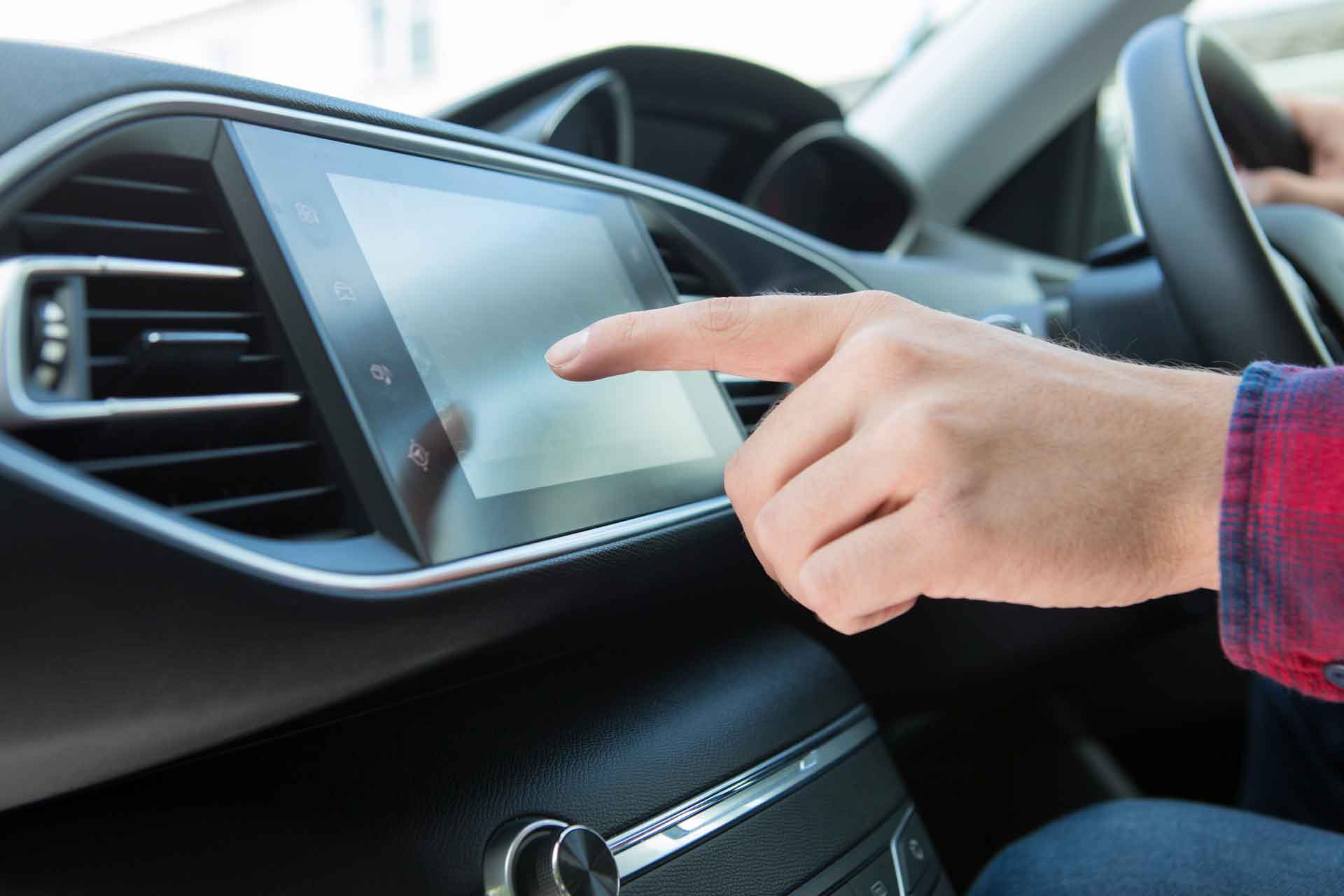 Finger pointing to touchscreen in car dashboard